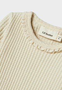 Cremefarvet ribbet pullover med en flæsekrave. Blød tekstur med et subtilt mønster. Etiketten siger "Lil'Atelier" i størrelse 1-2M.