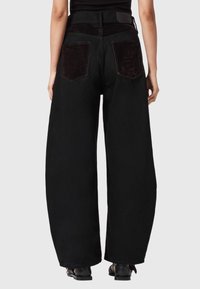 Jeans negri cu picioare largi și talie înaltă. Fabricat din denim, cu buzunare dintr-un material negru contrastant și o finisare netedă.