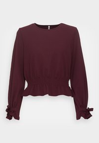 Burgunderfarbener Langarmtop mit geraffter Taille und Rüsche am Saum. Verfügt über elastische Säume mit Schleifendetails. Hergestellt aus einem glatten Stoff.