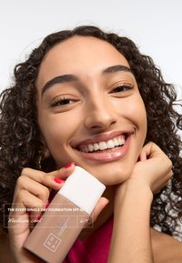 Botella de base con un cuerpo beige mate y una tapa blanca brillante, etiquetada "The Every Single Day Foundation SPF 50, Medium Cool."