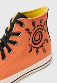 Πορτοκαλί πάνινο παπούτσι υψηλής κοπής με μαύρα κορδόνια, διακοσμημένο με κεντητό μοτίβο ήλιου στο πλάι και κίτρινη εσωτερική επένδυση.