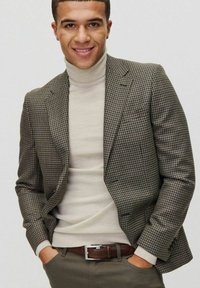 Brązowa i szara marynarka w jodełkę, kremowy golf, brązowy pasek, oliwkowe spodnie. Slim fit, teksturowany materiał z wyraźnymi klapami i kieszeniami naszytymi.