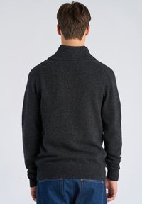 Dunkelgrauer Strickpullover mit hohem Kragen, gerippten Bündchen und Saum, mit glatter Textur und figurbetontem Design. Rückansicht dargestellt.