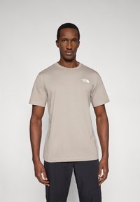 Μπεζ κοντομάνικη μπλούζα με στρογγυλή λαιμόκοψη, κατασκευασμένη από μαλακό ύφασμα. Διαθέτει μικρό λευκό λογότυπο στο στήθος και άνετη εφαρμογή.