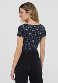 Top corto nero a maniche corte con motivo floreale che presenta rose blu. Tessuto leggero con una texture liscia. Collo rotondo classico, design aderente.
