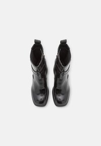 Schwarze Leder-Ankle Boots mit schlankem Design, quadratischen Zehen, elastischen Seitenpaneelen und Zuglaschen für einfaches An- und Ausziehen. Glatte, glänzende Oberfläche.