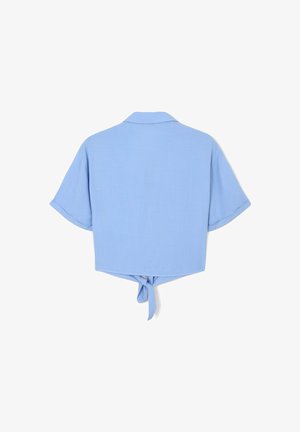 Camicetta azzurro chiaro corta con maniche corte, colletto e dettaglio annodato sul retro. Texture liscia, design semplice, senza loghi o decorazioni visibili.