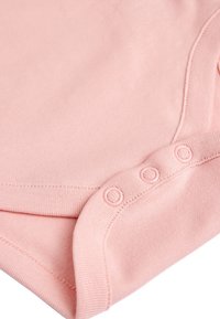 Pink cotton onesie featuring a round neckline and snap fastenings at the bottom. Smooth texture with flat seams and no patterns.