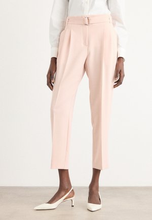 Pantalons ajustés rose pâle avec des plis, taille haute et détail de boucle en ton argent. Le tissu est lisse, avec un design de jambe courte.