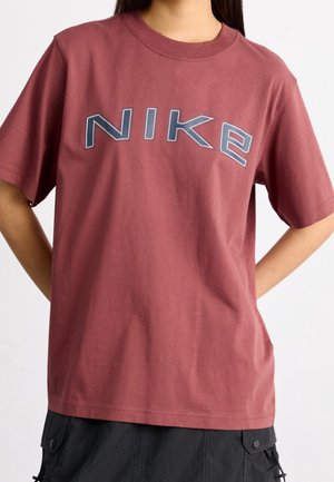 Bordeauxrode katoenen T-shirt met korte mouwen en ronde hals, met een opvallend grijs Nike-logo in vetgedrukte letters op de borst.