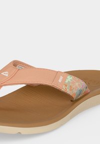 Καφέ και μπεζ σαγιονάρα με ροδακινί λουλουδάτο υφασμάτινο λουράκι και το λογότυπο "REEF" στο πλάι, με ανάγλυφο πάτο και σόλα.