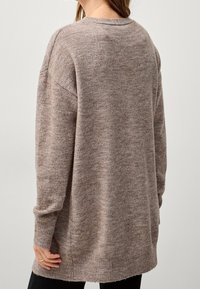 Brązowy sweter z dzianiny o luźnym kroju, długimi rękawami, ściągaczami na mankietach i zaokrąglonym dołem, charakteryzujący się miękką fakturą.