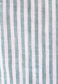 Tissu blanc avec des rayures verticales vert-bleu uniformément espacées dans un motif de texture tissée.