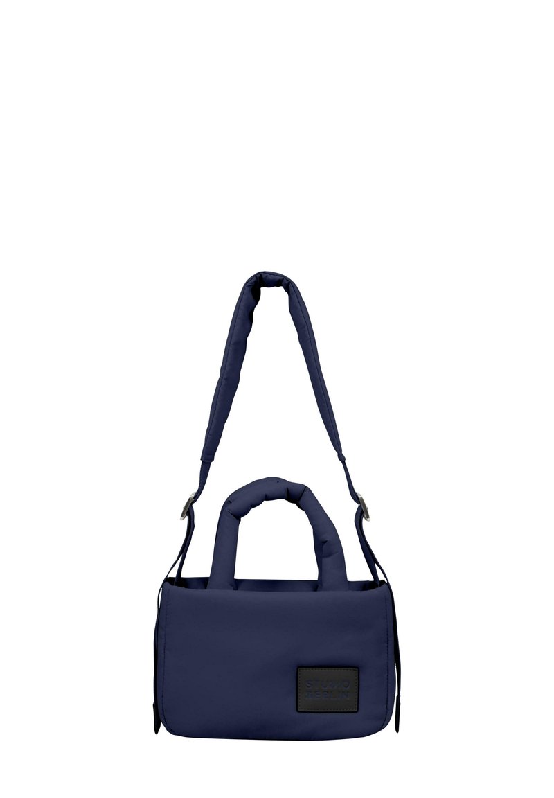 Borsa imbottita di colore blu navy con due manici corti e una tracolla staccabile, dotata di un'etichetta in tessuto testurizzato sul davanti. Finitura del materiale liscia.