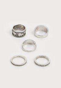 Lot de cinq bagues en argent présentant divers designs : l'une avec un bandeau détaillé, les autres lisses ou décorées de textures contrastées.