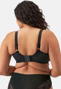 Mustat rintaliivit, joissa on säädettävät olkaimet, pitsikuviointi ja moninappikiinnitys takana. Silkkinen kangas, jossa on aallotettu reuna.