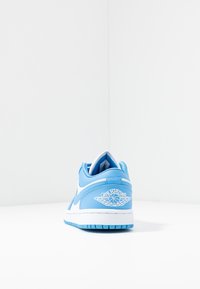 Ljusblå och vita Air Jordan-sneakers visade från baksidan på en vit yta mot en vit bakgrund.