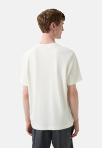 Hvid kortærmet t-shirt i et glat, letvægtsmateriale. Crew neck-design med en afslappet pasform, der har en ensfarvet ryg uden mønstre eller detaljer.