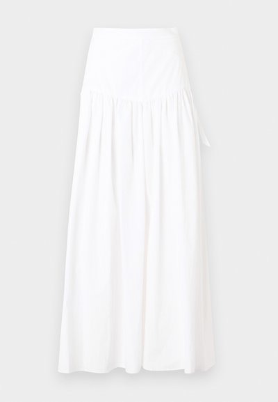 Μακριά λευκή φούστα με συγκεντρωμένη μέση και διακριτική λεπτομέρεια δέσιμου στο πλάι, φτιαγμένη από ελαφρύ ύφασμα, σε απλό φόντο.