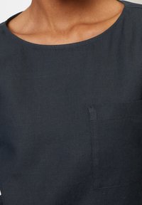 Tmavě modrá lněná košile s širokým výstřihem, krátkými rukávy a náprsní kapsou s čistým, jemným provedením.