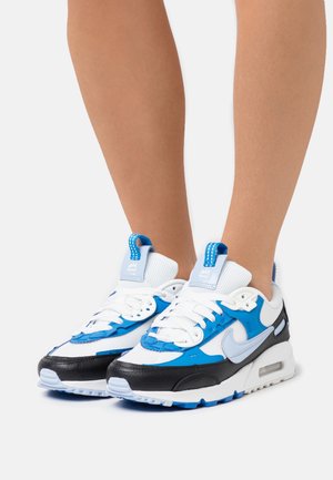 Blå och vita Nike Air Max-sneakers har ett överdel i mesh och läder, texturerade detaljer, en synlig luftenhet och svarta accenter.