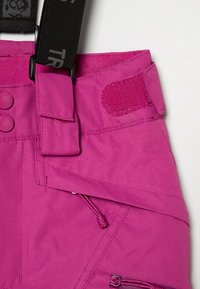Roza smuča hlače z nastavljivimi črnimi trakovi, zapenjanjem na gumbke in velcro priponko. Imajo zadrgo žepov in strukturirano tkanino za trajnost.