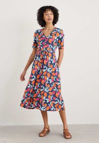 Floral dress with short sleeves, v-neck, featuring a navy background and vibrant orange, pink, and teal leaf patterns. Mid-length design.