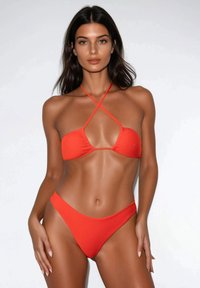 Set di bikini rosso con top triangolare e spalline incrociate, e slip a vita alta. Tessuto liscio senza motivi o decorazioni.