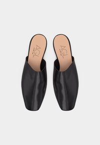 Ζευγάρι μαύρα δερμάτινα πάνινα παπούτσια χωρίς κορδόνια με τετράγωνα μύτες και ταμπά εσωτερικές σόλες με το λογότυπο "AGL", παρουσιάζονται σε λευκό φόντο.