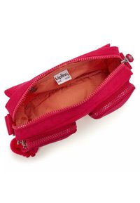 Rosa tygpåse med två dragkedjefack, mjukt material och orange foder. Har en sidopom-pom-detalj och en varumärkesetikett inuti.