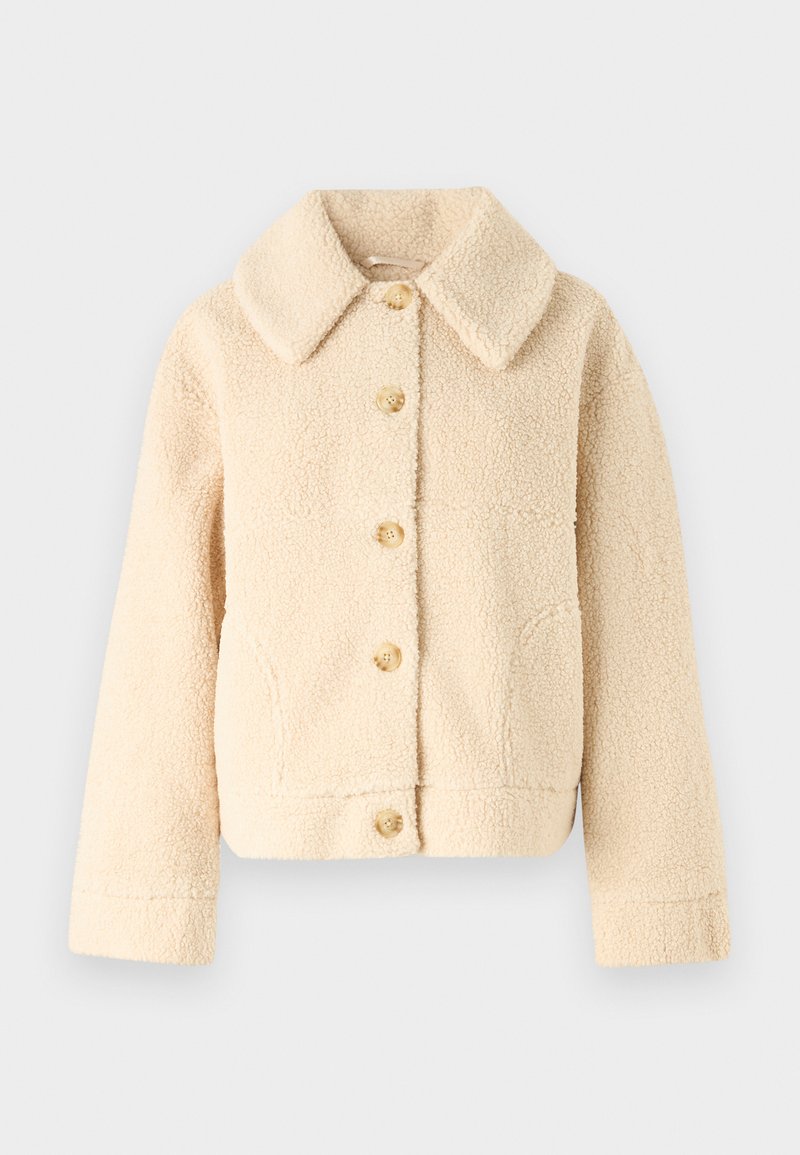 Beżowa polarowa kurtka z kołnierzem, zapięcie na guziki z przodu i dwiema bocznymi kieszeniami. Cechuje się miękką, teksturowaną powierzchnią oraz skróconym fasonem.