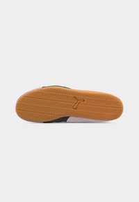 Σόλα παπουτσιού με πορτοκαλί καουτσούκ πέλμα που διαθέτει μοτίβο σαν ελαστικό και λογότυπο puma ανάγλυφο στο κέντρο, σε λευκό απλό φόντο.