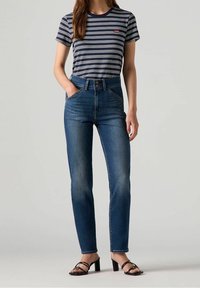 T-shirt rayé bleu marine à manches courtes, associé à un jean bleu taille haute. Le jean présente une coupe slim et un design classique à cinq poches.