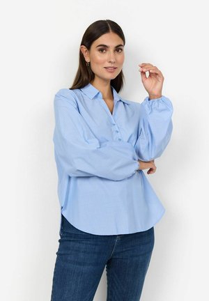 Light blue button-up shirt with vertical stripes, a relaxed fit, and puffed sleeves. Styled with dark denim jeans.