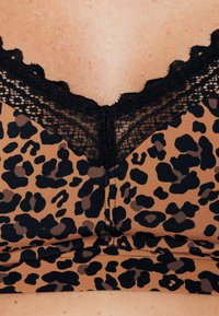 Bralette in stampa leopardata color beige con dettagli neri, caratterizzato da un delicato bordo in pizzo nero lungo lo scollo e una texture morbida.
