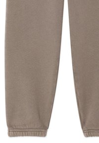 Lichtbruine sweatpants met een zachte, gestructureerde stof, elastische manchetten en een ontspannen pasvorm. Geen zichtbare patronen of accenten.