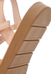 Rose gold sandal with adjustable straps, featuring a glitter accent and a textured rubber sole with horizontal grooves.