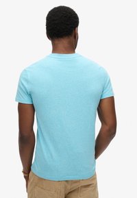 T-shirt azzurro chiaro a maniche corte con scollo rotondo, realizzato in un tessuto morbido e texturizzato. Design semplice, senza motivi o accenti visibili.