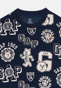 Felpa blu navy per neonati con vari loghi bianchi GAP, orsetti a cartoni animati e motivo testuale "Original GAP Since 1969".