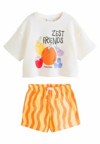 Short-sleeve cream crop top with fruit graphic and text "ZEST FRIENDS FOREVER." Paired with orange shorts featuring wavy stripes.