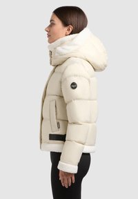Light cream puffer jacket with a faux fur-lined hood, elastic cuffs, a zippered pocket, and a black accent panel at the waist.