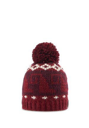 Bonnet d’hiver bordeaux tricoté avec des motifs géométriques blancs et un grand pompon sur le dessus, bord-côte et petite étiquette en tissu sur le côté.