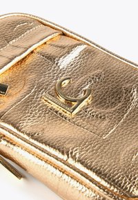 Borsa a tracolla in pelle testurizzata metallizzata dorata con un logo dorato a forma di "C" in rilievo e cuciture dettagliate sulla patta frontale.