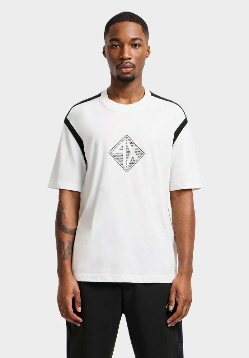 T-shirt bianca a maniche corte con grafica a diamante nera, caratterizzata da dettagli neri sulle spalle e una vestibilità morbida, in morbido cotone.