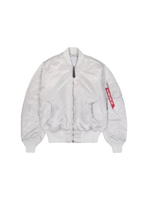 Fehér bomber dzseki elülső cipzárral, két nyomógombos zsebbel, bordás mandzsettákkal és szegéllyel, valamint cipzáras karzsebbel, amelyen piros "Remove Before Flight" címke található.