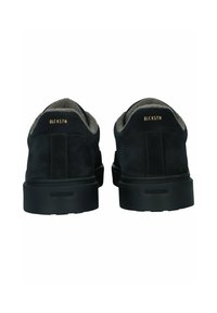 Schwarze Wildlederschuhe mit einem grauen Fleece-Futter, runder Zehenform und schwarzer Gummisohle. Mit goldenen Logo-Details auf der Rückseite.