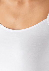 White tank top with a soft, ribbed texture and wide straps. Features a rounded neckline, highlighting a smooth, minimalist design.