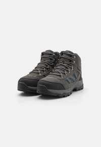Graue Wanderschuhe aus einer Kombination von strukturiertem Mesh und synthetischem Material, mit verstärkter Zehenpartie, Metallösen und einer robusten Gummilaufsohle.