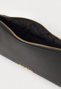Clutch in pelle nera con chiusura a zip dorata. L'interno è foderato in tessuto e presenta un'etichetta del brand. Texture liscia e design elegante.