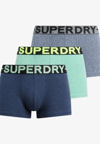 Trzy pary męskich slipów w kolorze granatowym, jasnoniebieskim i szarym. Każda para ma czarny pas z napisem "SUPERDRY" w kontrastowych kolorach.